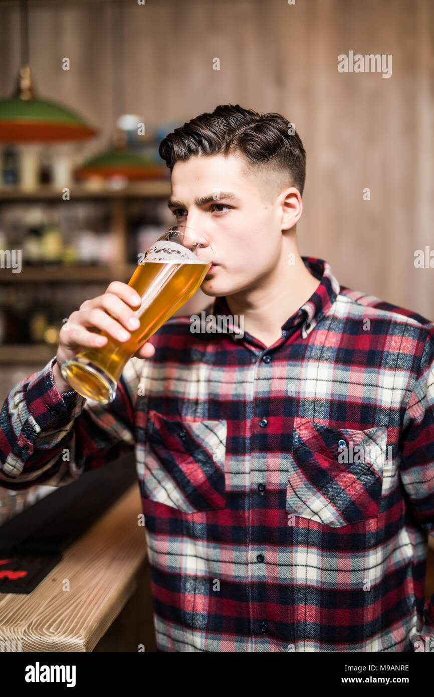 Man drinking beer. Side view of handsome young man drinking beer while