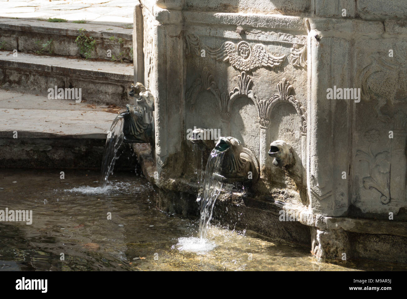 A carved marble fountain with pure water, called Immortal Water, on the main square of the traditional greek village Makrinitsa, Pelion peninsula Stock Photo