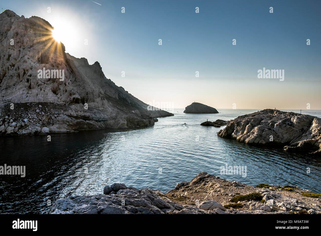 Mediterranean sea view with rocky mountains hiding the rays of the sun under a clear sky in Les calanques, Marseille, France. Stock Photo