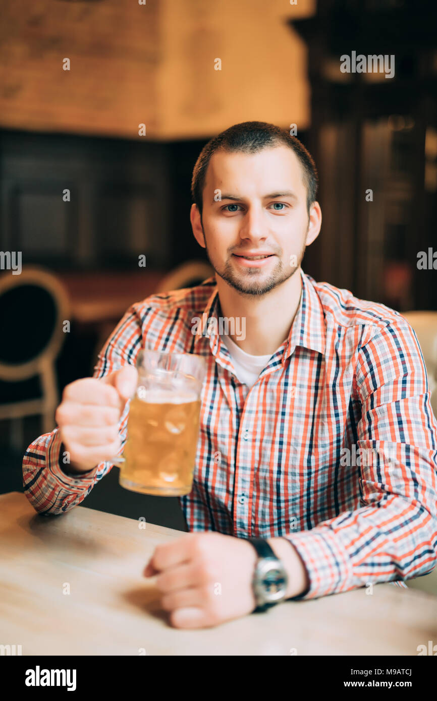 Man drinking beer, handsome young man drinking beer while sitting at