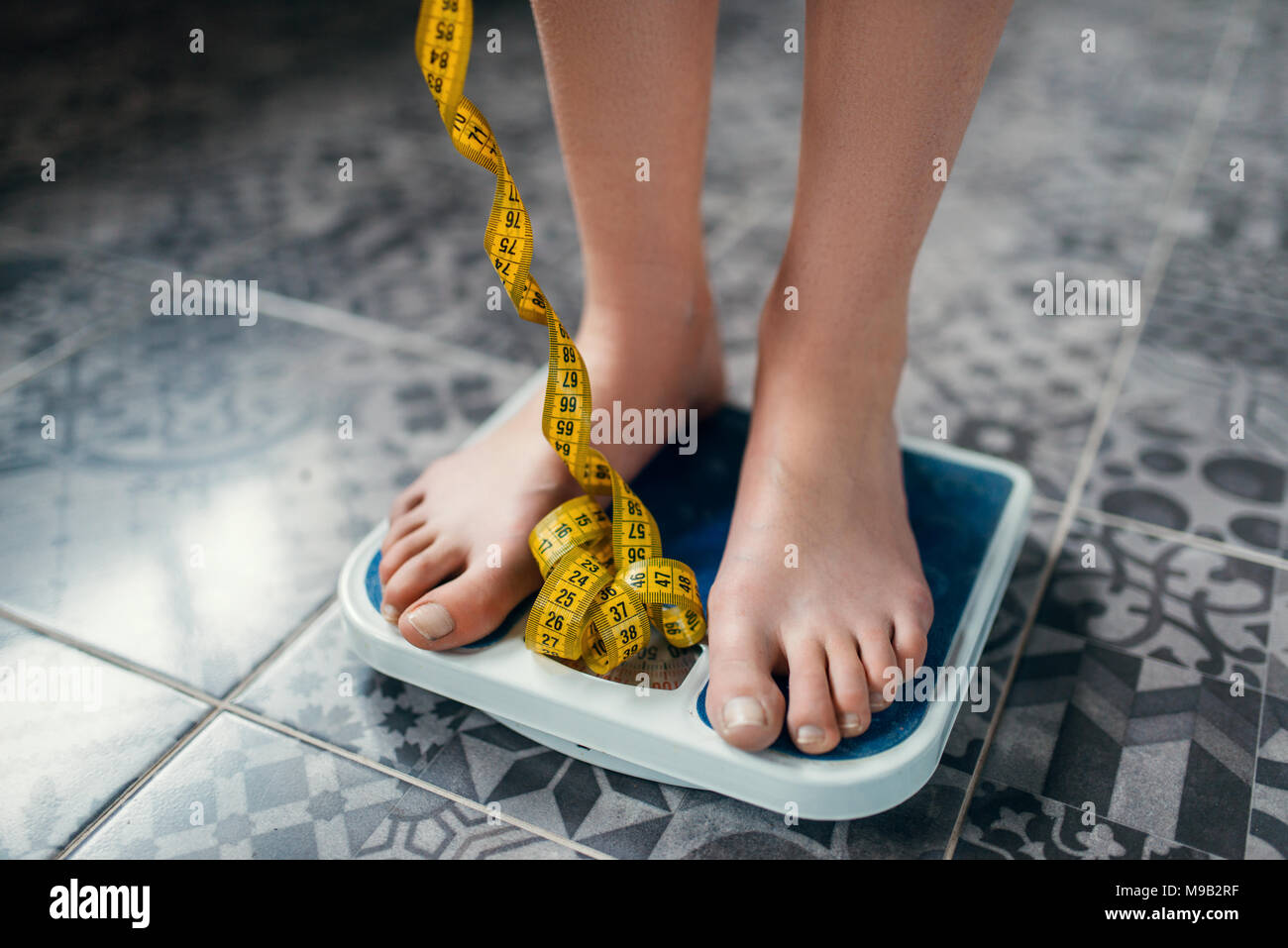 Female feet on the scales closeup, measuring tape Stock Photo Alamy