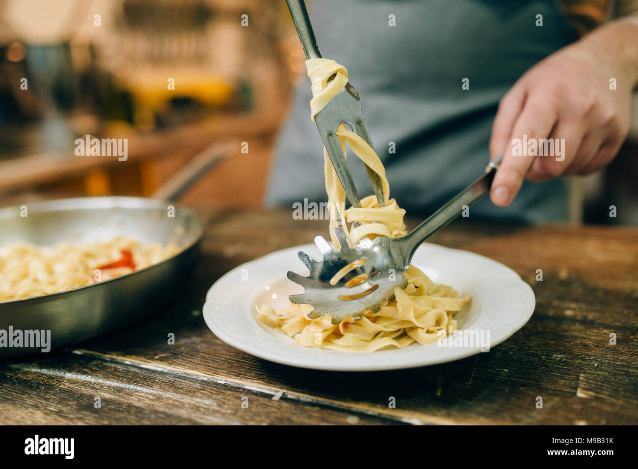 Pasta Thouges For Chef Male chef puts fresh pasta in a plate Stock Photo - Alamy