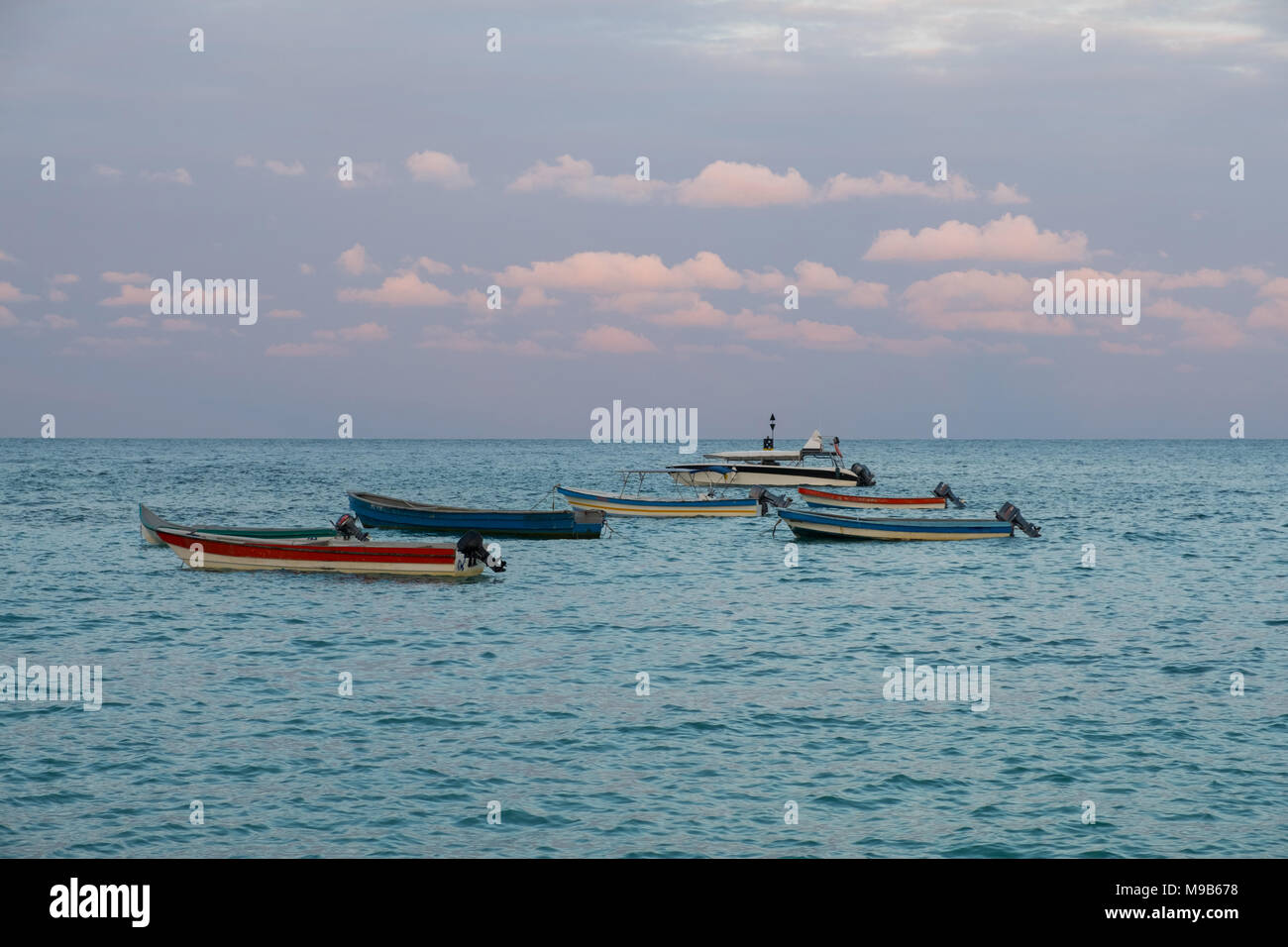 small wooden boats, motorboats on ocean horizon in evening sun - Stock Photo
