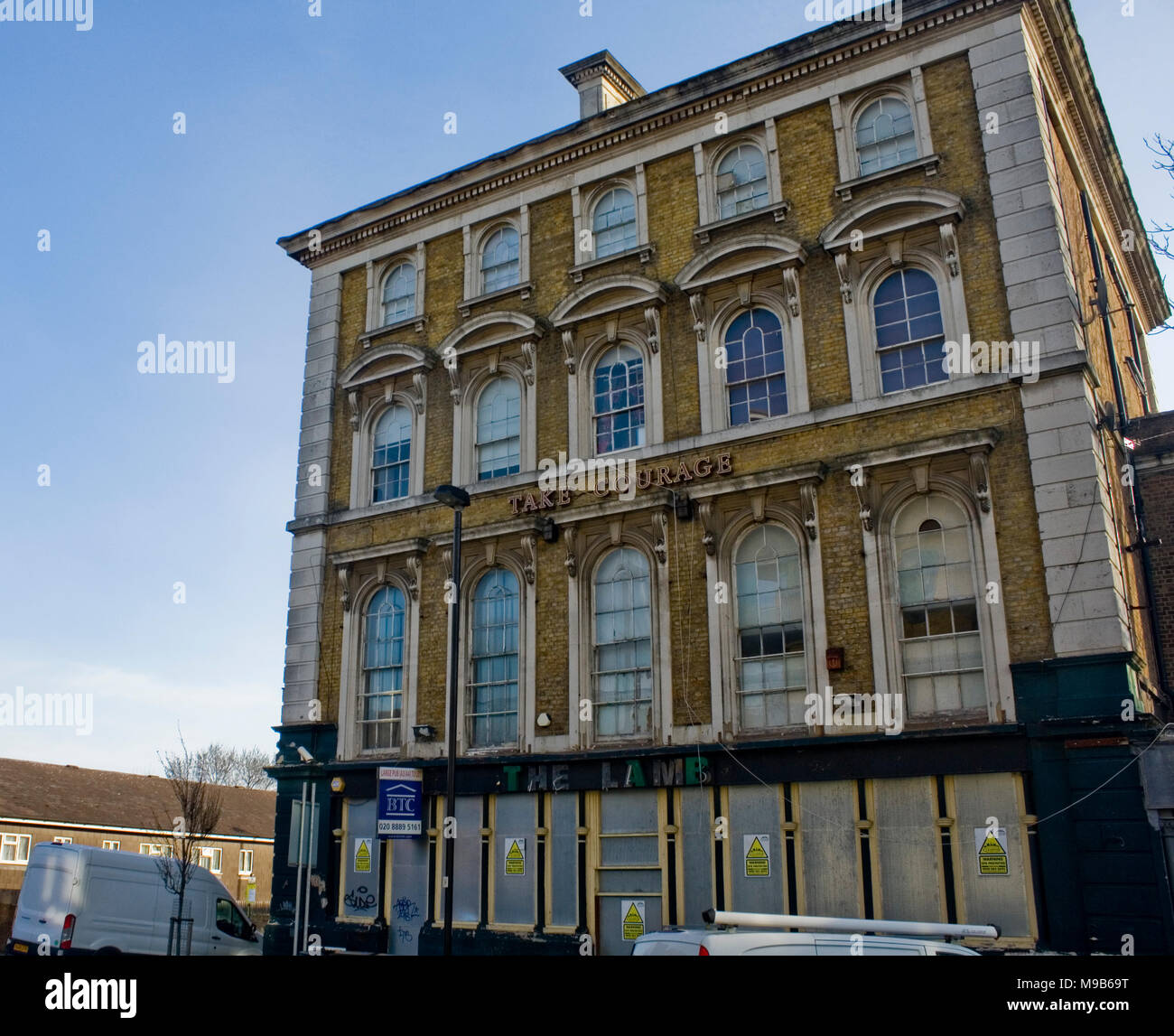 Take Courage sign yellow london stock brick building Stock Photo