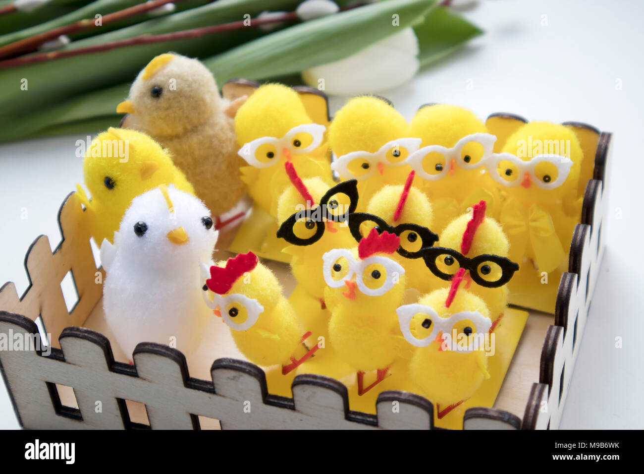 Fluffy yellow rag chicken with glasses in a wooden basket as a ...