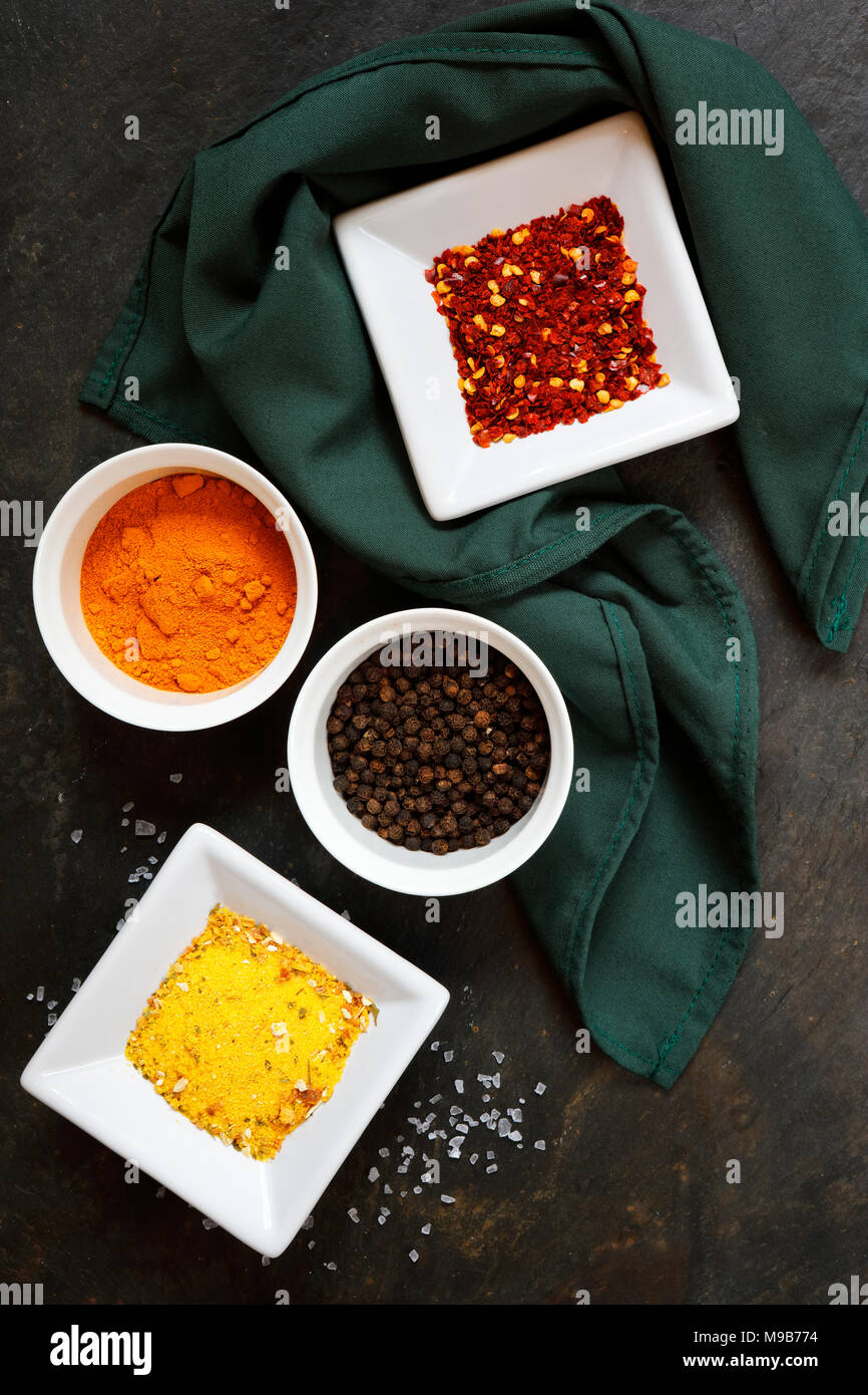 Various spices with peppercorn, cumin, hot peppers and turmeric on slate background Stock Photo