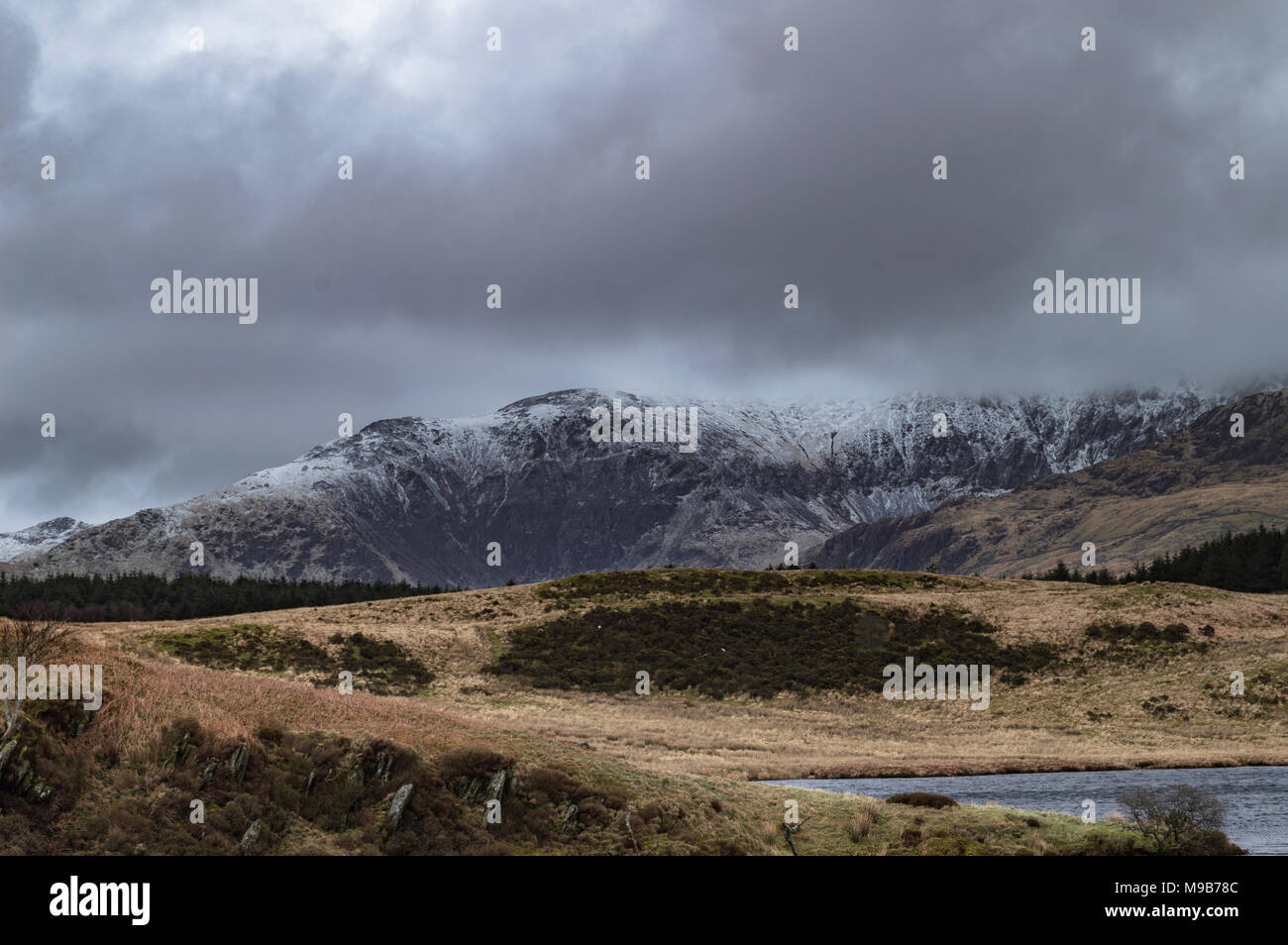 View across Llyn Y Dywarchen to a snow covered mount Snowdon in the Snowdonia National Park, Wales. Stock Photo