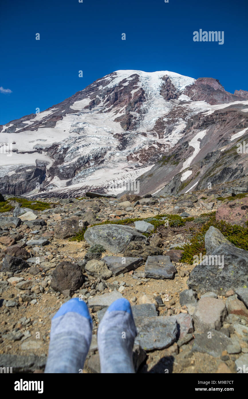 After a steep climb to edge of glacier and snow on Mount Rainier, a hiker sat down and removed