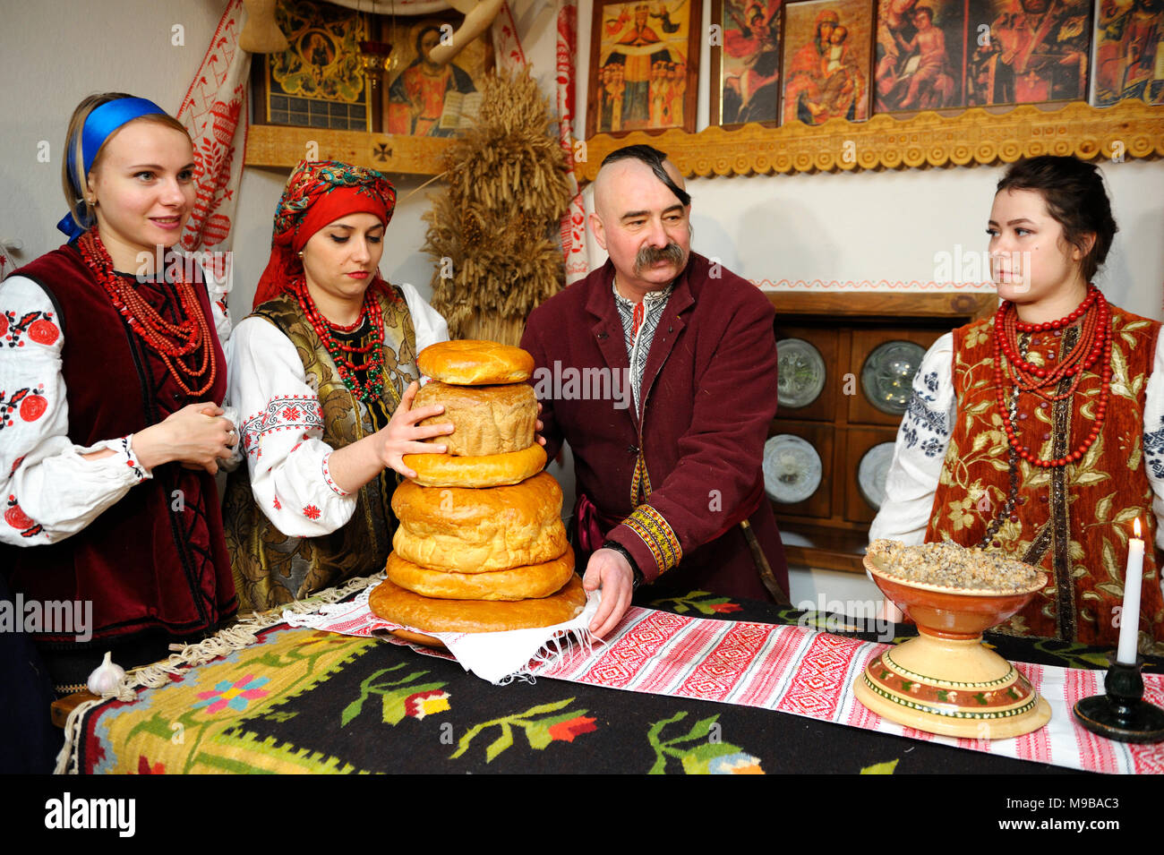 People in Ukrainian native dresses stand behind table set with traditional Easter breads before All-night service.March 23,2018. Kiev,Ukraine Stock Photo