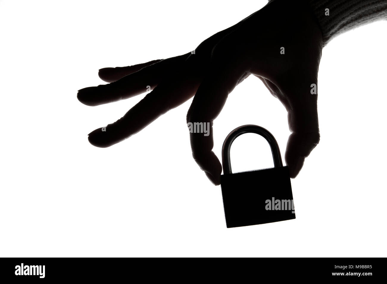 Silhouette of a hand holding a padlock on a plain white background. Security and privacy. Stock Photo