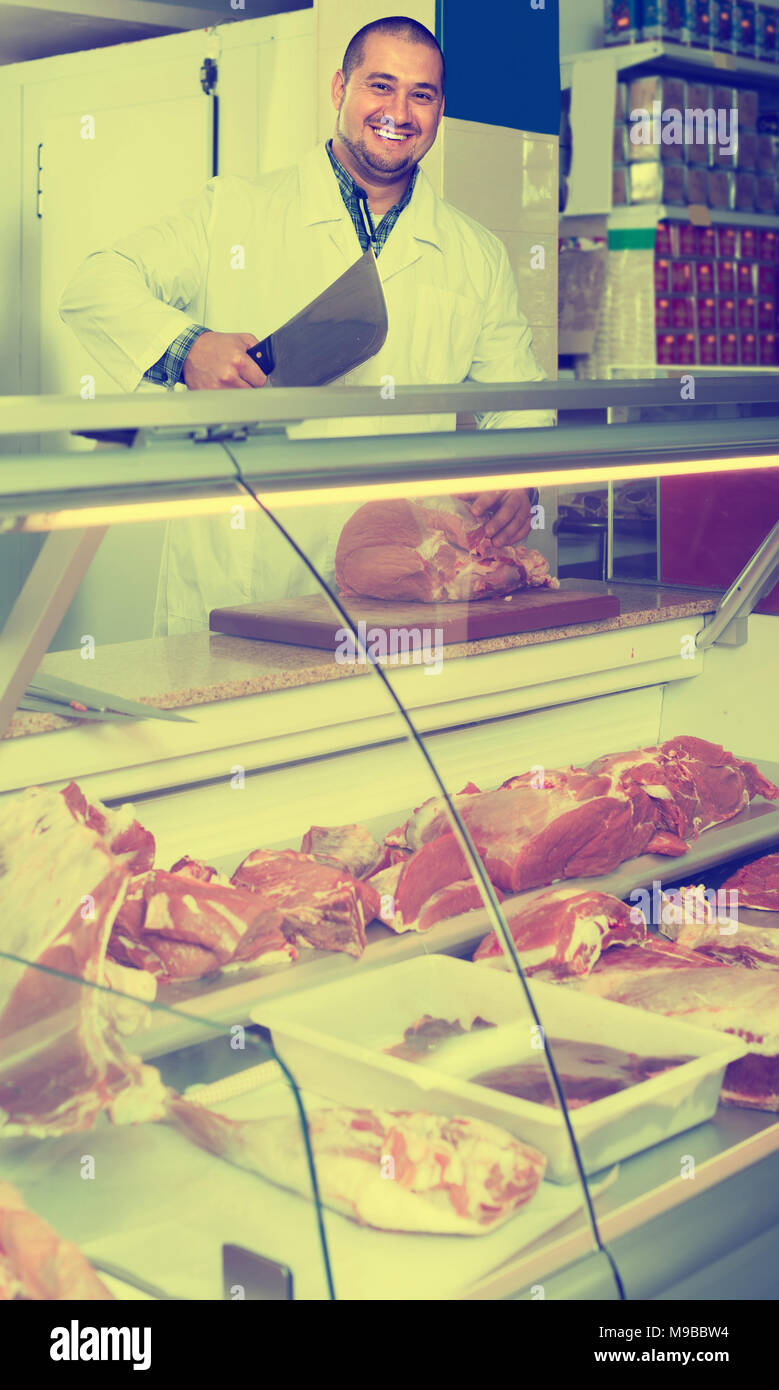 Portrait of positive russian male butcher in kosher section at ...