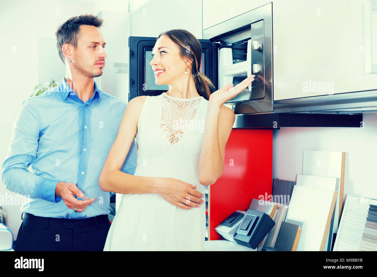 Adutl couple is choosing new microwave in kitchen furnishing store. Stock Photo