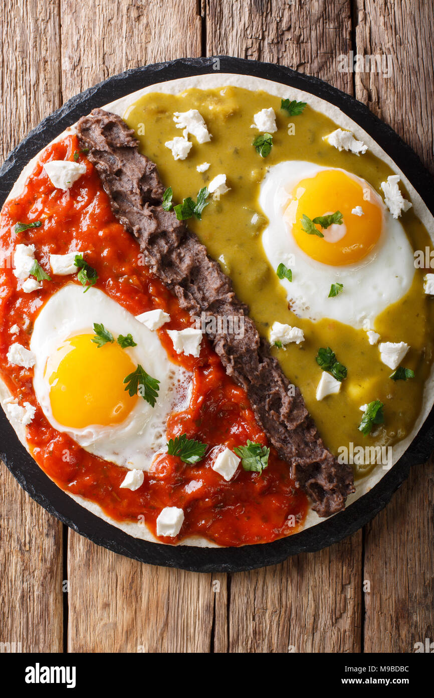 huevos divorciados, fried eggs on corn tortillas with two salsas, mexican breakfast. Vertical top view from above Stock Photo