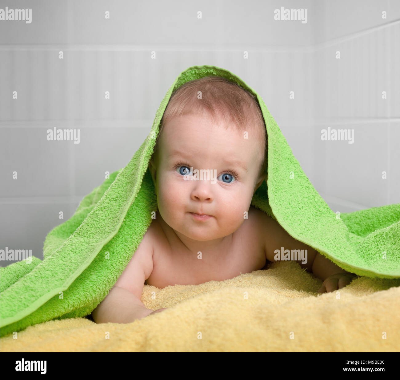 cute baby in colorful bathing towel in bathroom Stock Photo