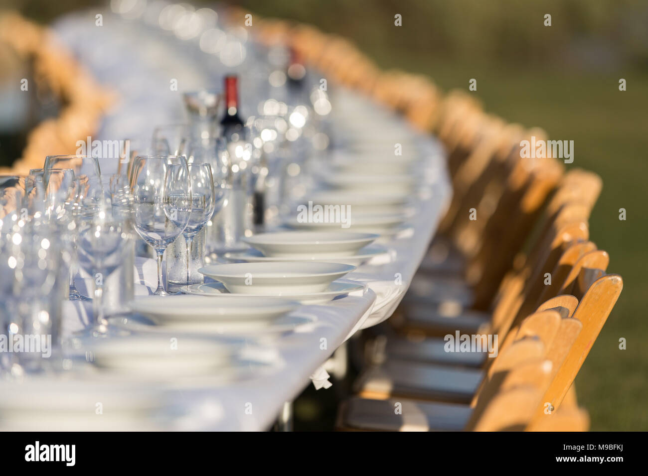 A long table with wine glasses at an outdoor event Stock Photo