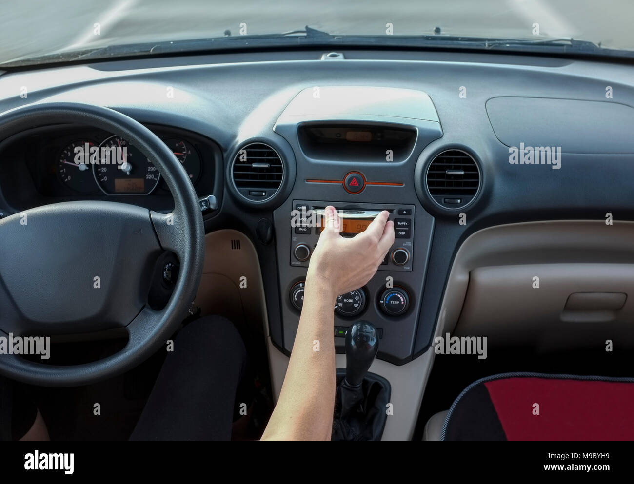 Woman inserting CD Audio while she is driving. Cause of Distracted Driving Accidents concept. Inside car view Stock Photo