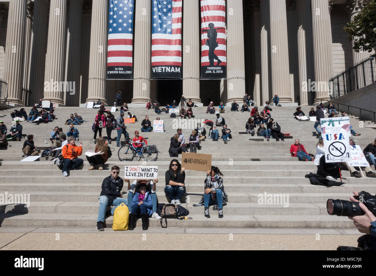 Washington, DC.  24th April, 2018.  On the steps of the national Archives, ironic banner above, some of the hunndreds of thousands of protesters take a break during the massive rally on Pennsylvania Ave. demanding that safety and the end of gun violence becomes a priority, and protesting government inaction on gun control, and the National Rifle Association’s influence on congress. Bob Korn/Alamy Live News Stock Photo