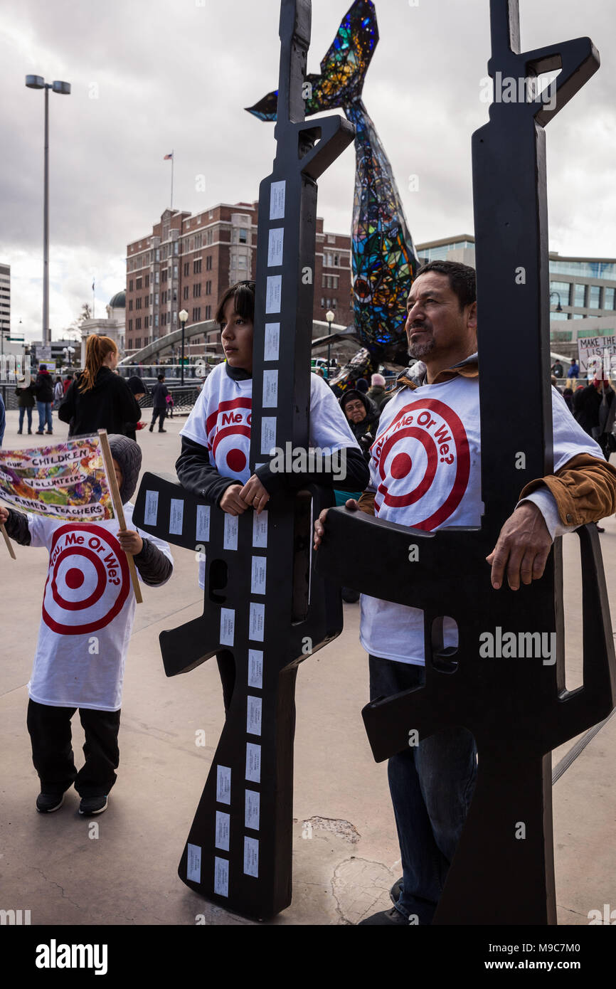 Reno, Nevada, USA. 24th Mar, 2018. FERNANDA VELAZQUEZ, age 13, and RICARDO MARTINEZ hold headstone assault rifles during the March for Our Lives event at Reno City Plaza in Reno, Nevada, on Saturday, March 24, 2018. Velazquez's rifle displays names and dates of people killed in mass murders. Artist Gene Gardella created the rifles as a way of making his voice heard. He said his motto while creating the pieces was, ''No more headstones, no more assault rifles.''.The event is one of hundreds of similar events at cities around the country that have sprouted off a national march in Washington, Stock Photo