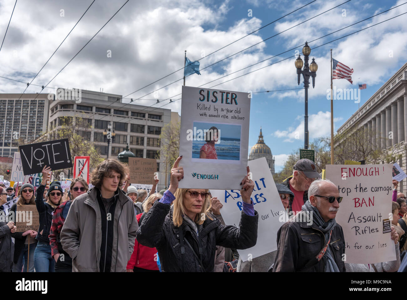 San Francisco, USA. 24th March, 2018. March for Our Lives rally and march to call for gun control and end gun violence; a woman marches carrying a sign that reads 'Sister killed by a 16-year-old with assault rifle 12/31/17' and ends with the hashtag #Enough (enough). Shelly Rivoli/Alamy Live News Stock Photo