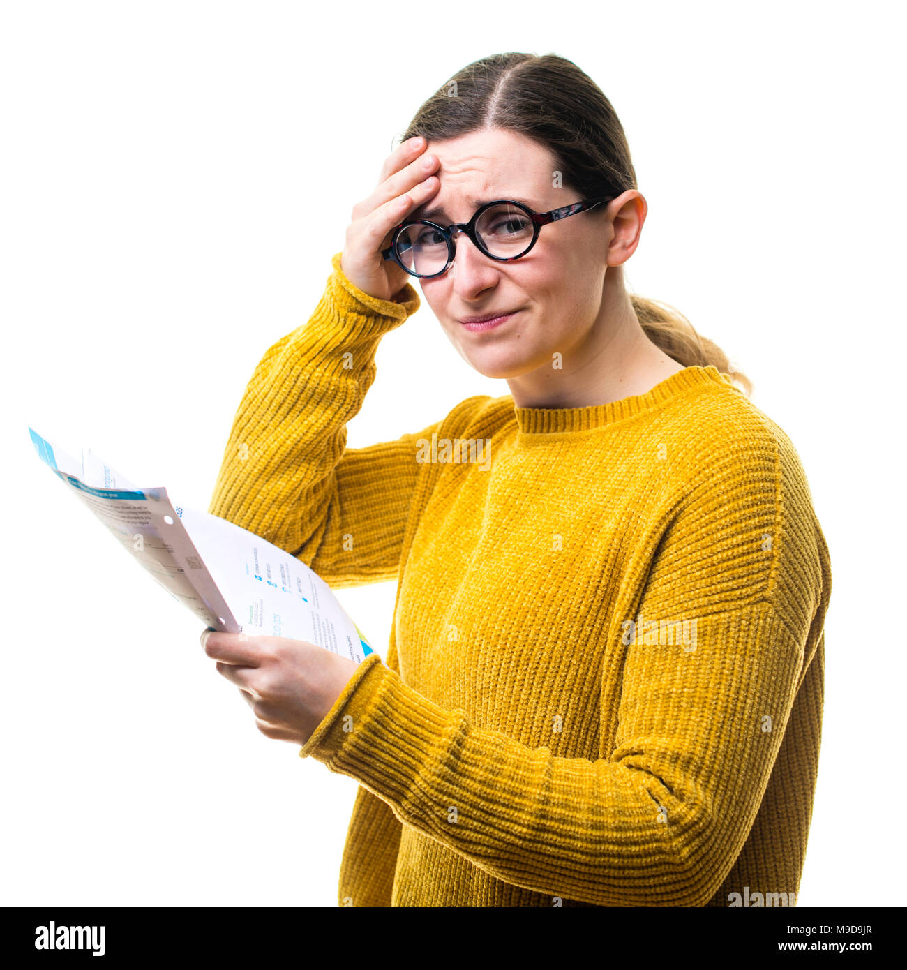 Money Worries and personal finances : A young Caucasian woman girl wearing a yellow jumper sweater, looking at her bills and worried about paying home domestic utility power charges , UK Stock Photo