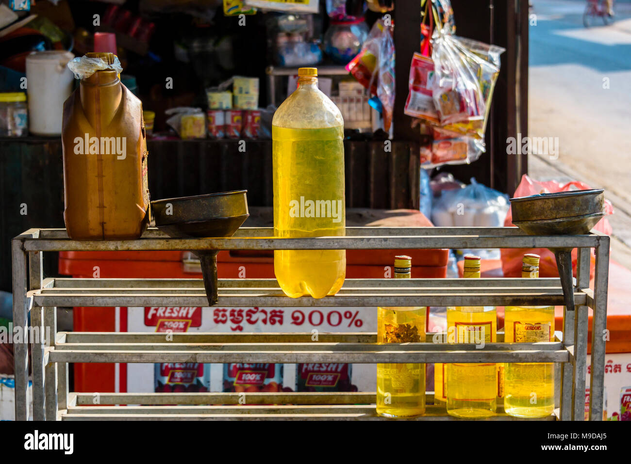 Bottles filled with petrol for sale at a street-side market stall to fuel scooters, Siem Reap, Cambodia Stock Photo