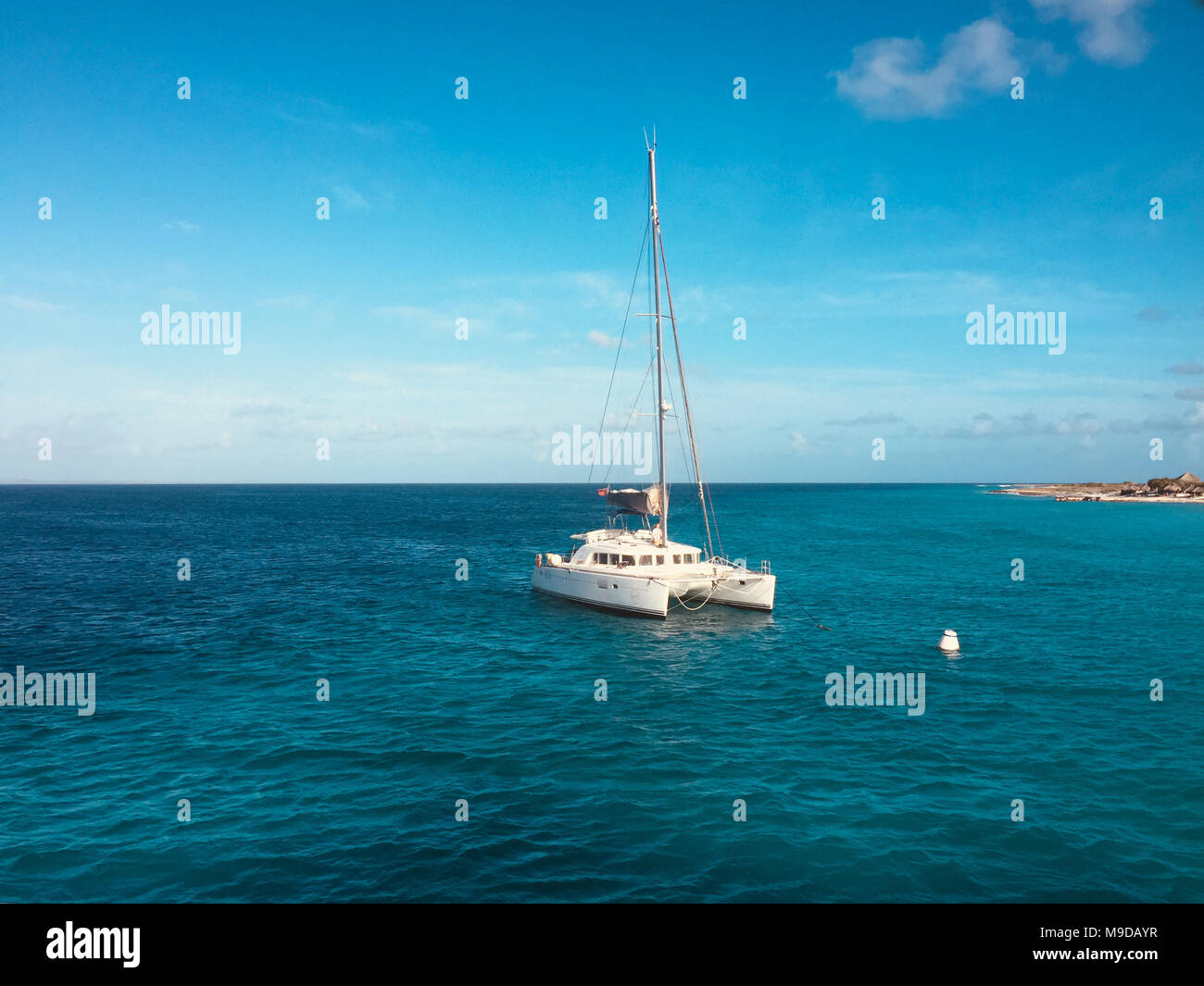 white  sailing boat catamaran on ocean near beach  - Stock Photo