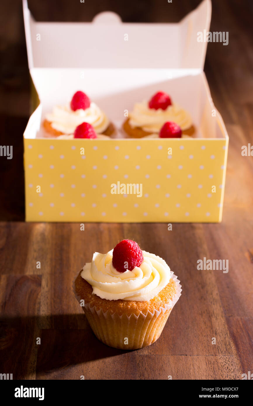 Lemon cupcakes with white chocolate butter icing topped with a fresh raspberry Stock Photo