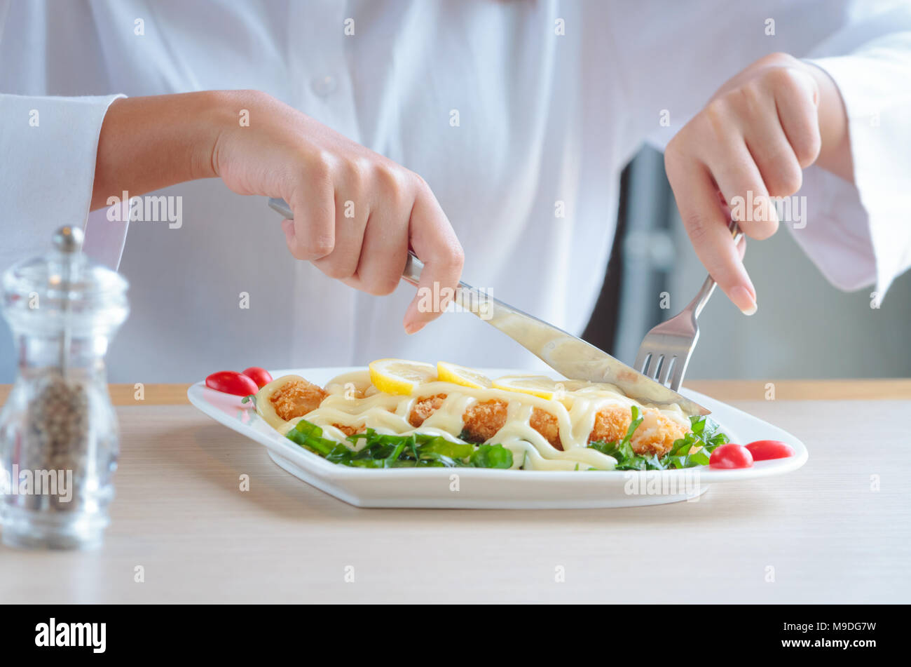 Woman hands cutting and eating delicious meal with knife and fork at