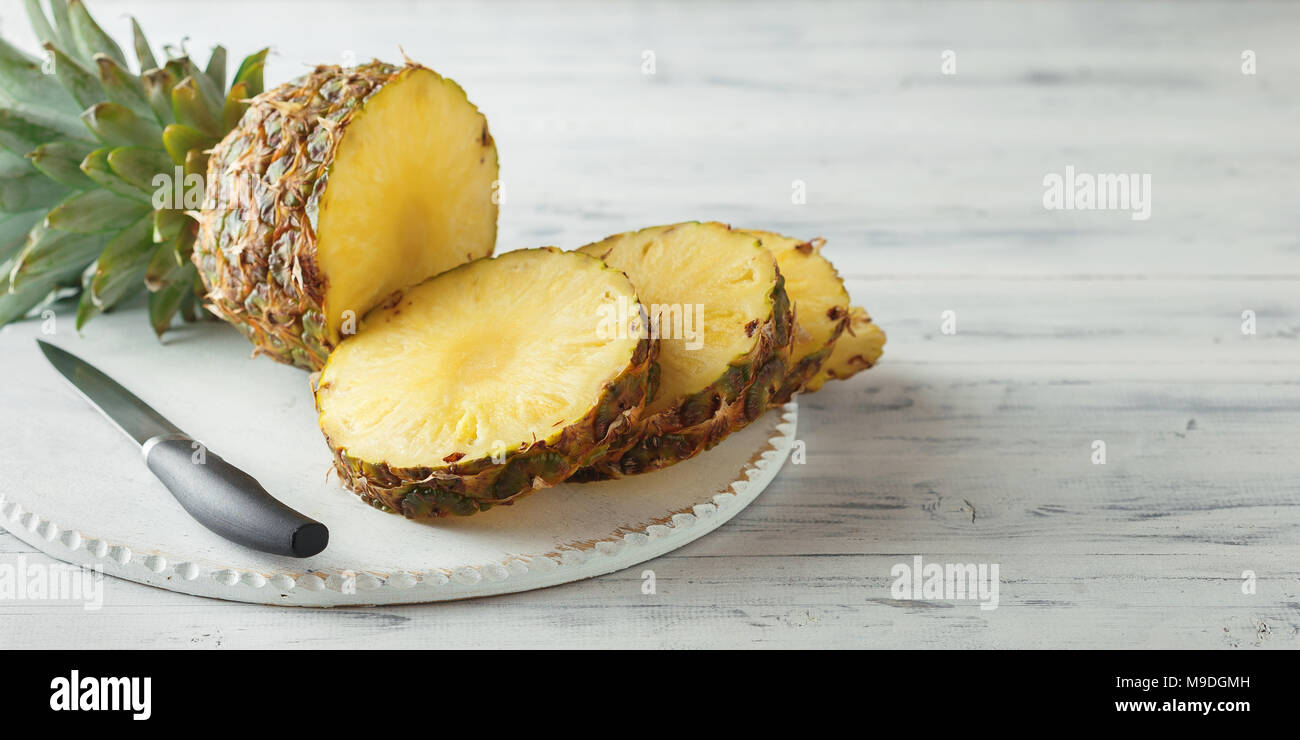 Fresh sliced pineapple on a white wooden cutting board. Top view Stock Photo