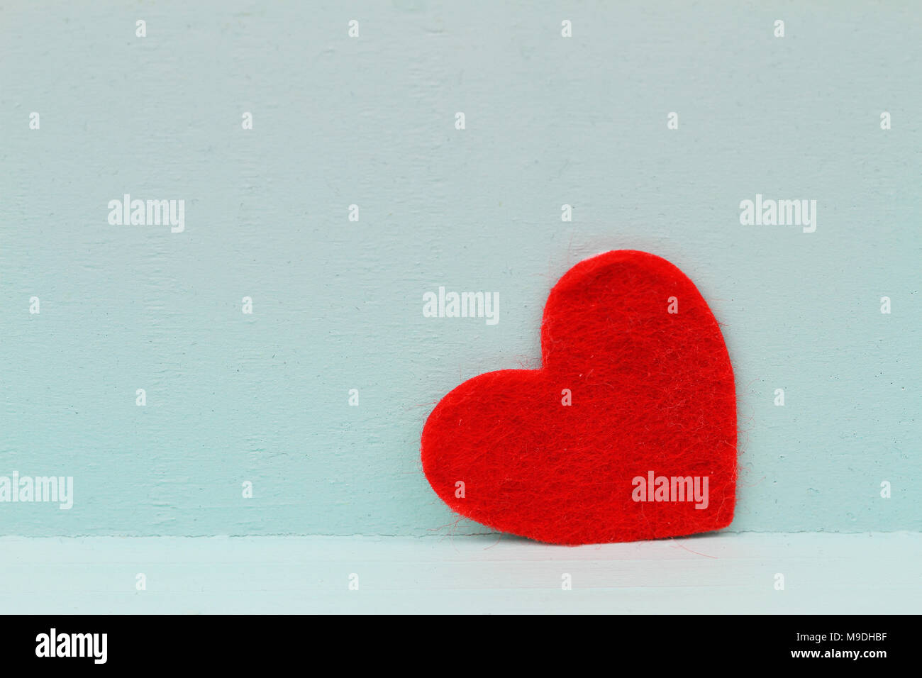 Red heart leaning against blue wooden surface with copy space Stock Photo