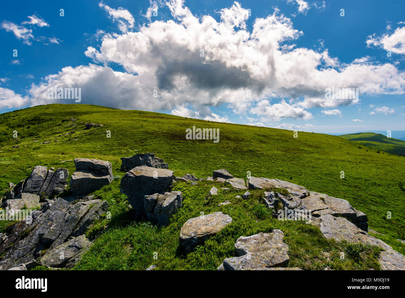 huge cloud rising behind the hill. gorgeous mountain landscape with boulders on grassy slopes Stock Photo
