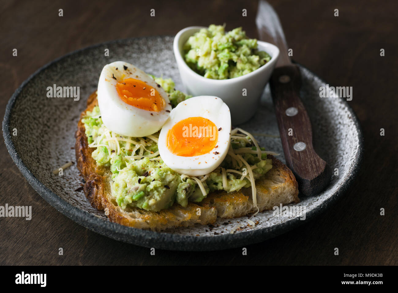 Toast with mashed avocado, egg and cheese on dark background. Closeup view. Healthy eating, healthy snack, lunch or breakfast Stock Photo