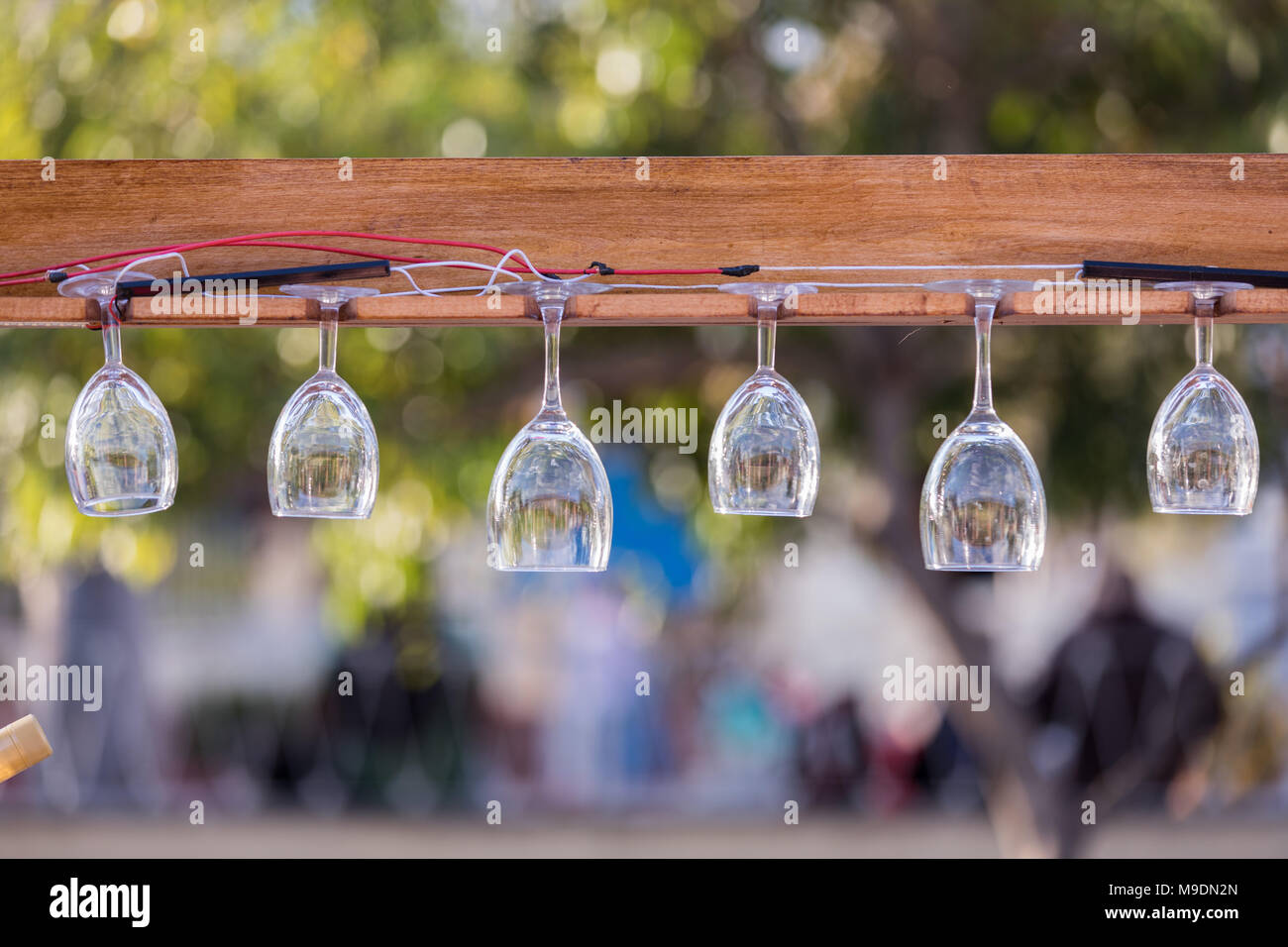 Several Wine Glasses hung on a board in a garden restaurant. Stock Photo