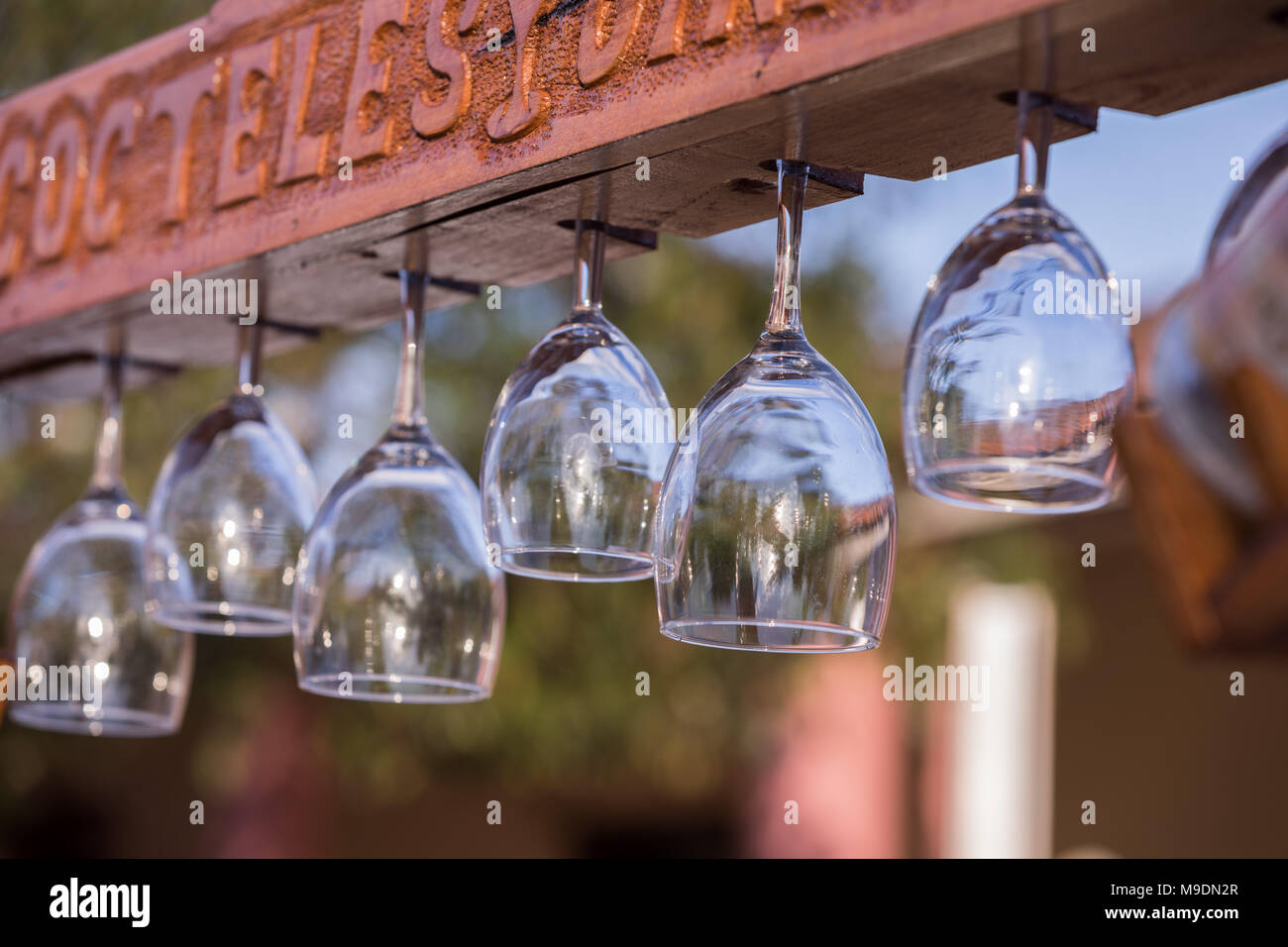 Several Wine Glasses hung on a board in a garden restaurant. Stock Photo