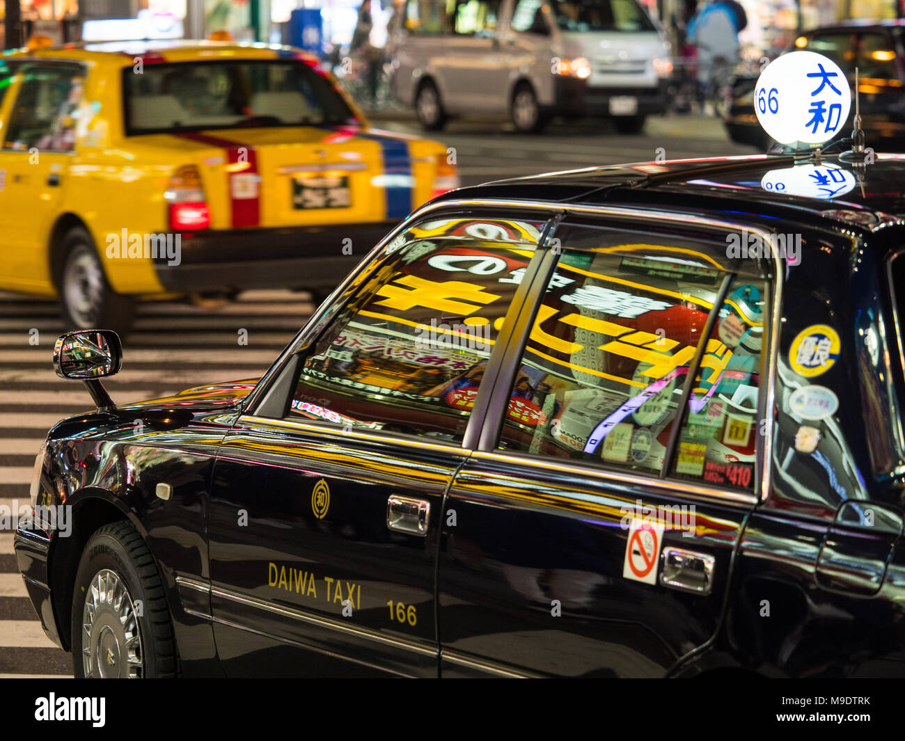 Tokyo Taxis Nightlife - vibrant lights reflect off Tokyo taxis  in the Shinjuku district Stock Photo