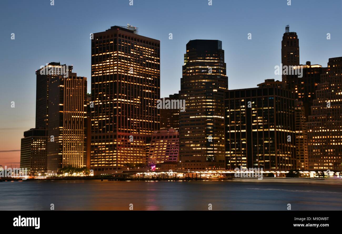 Wall Street and the skyline of downtown Manhattan from New York Harbor at dusk. Stock Photo