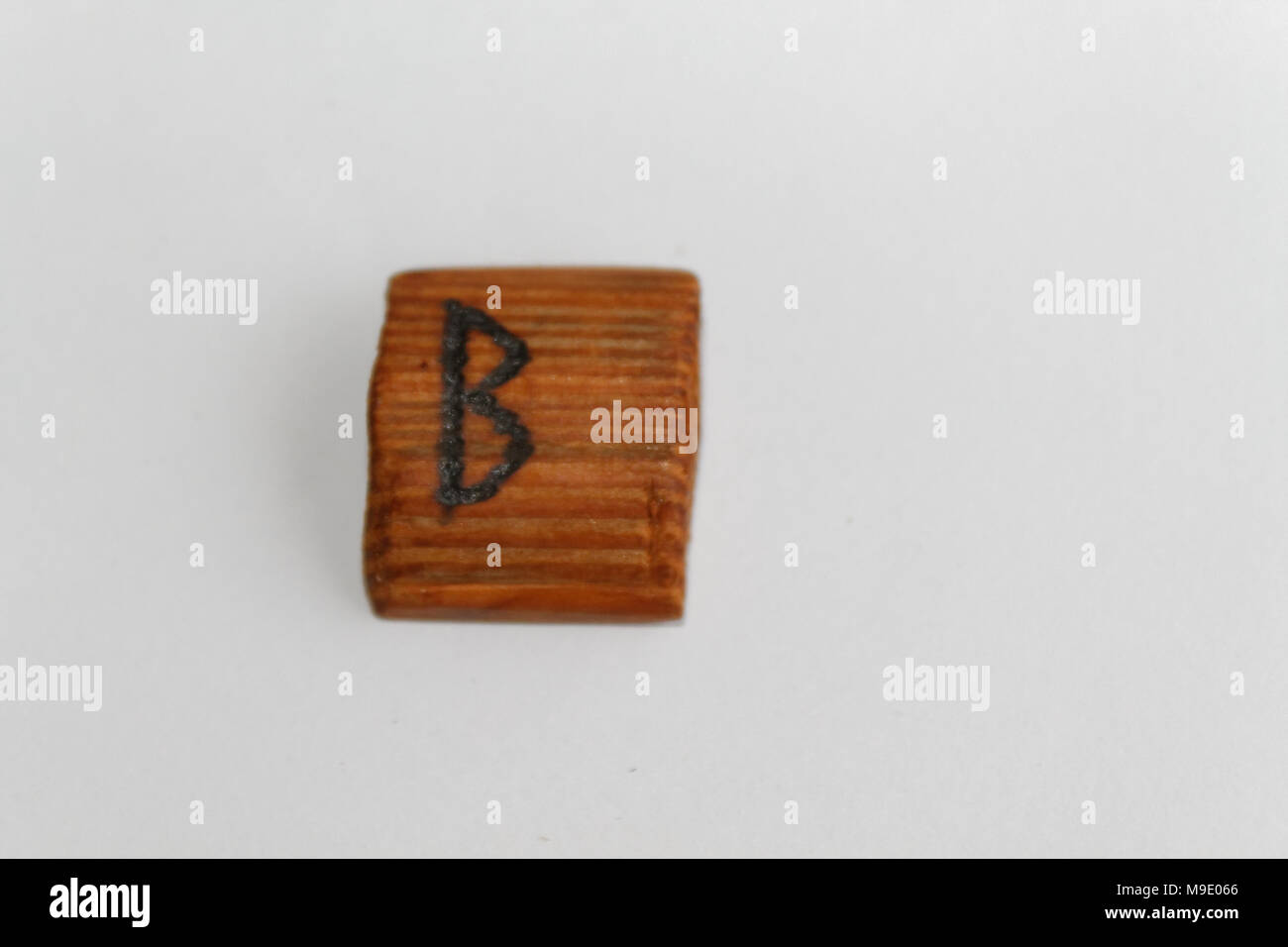 Wooden rune which means tree Birch, lie on a table on a white ...
