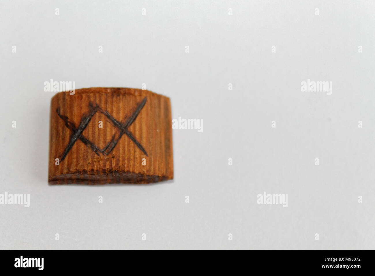 Wooden rune which means a gift, lie on a table on a white background Stock Photo