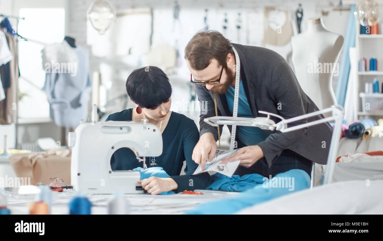 Male and Female fashion, designer, s are Working on Tailored Mannequin Wearing Clothes. They Also Use smartphone. In Their Studio Sewing Machine Stock Photo