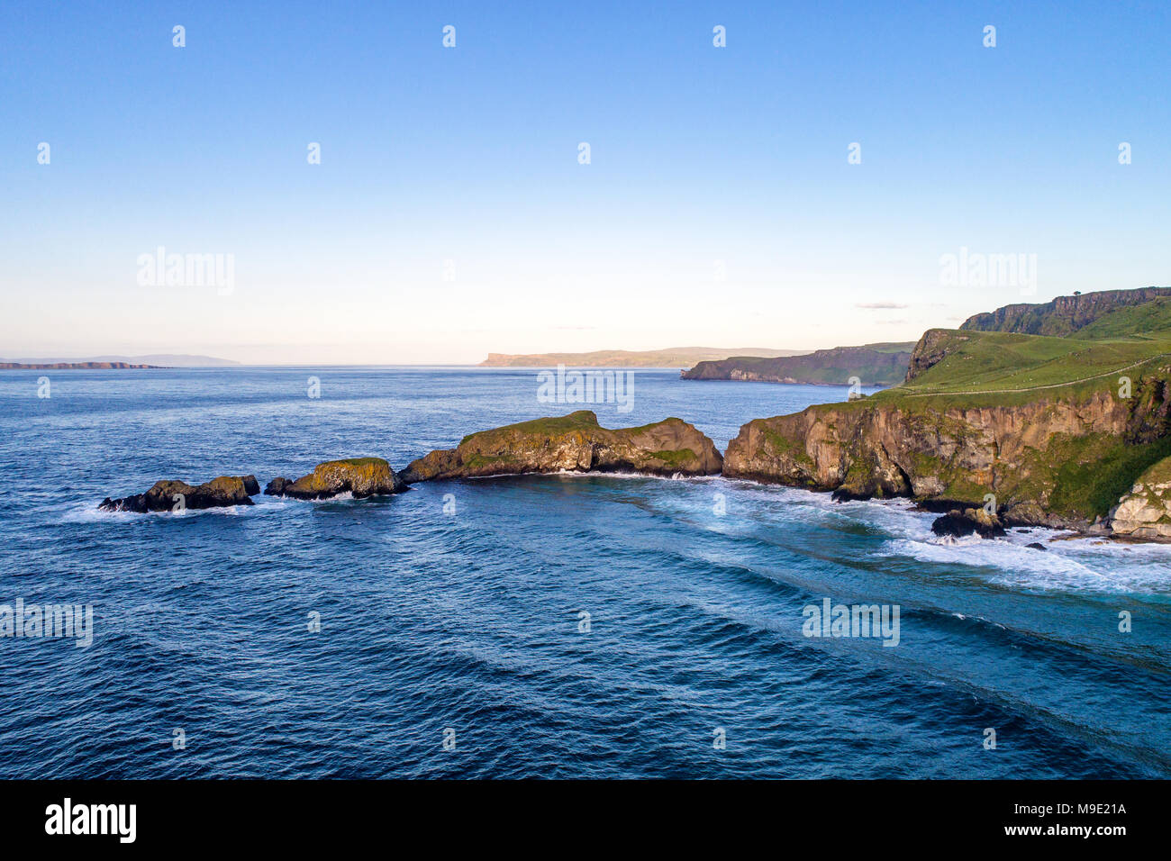 Northern Ireland, UK. Atlantic coast with cliffs and far aerial view of Carrick-a-Rede Rope Bridge in County Antrim Stock Photo