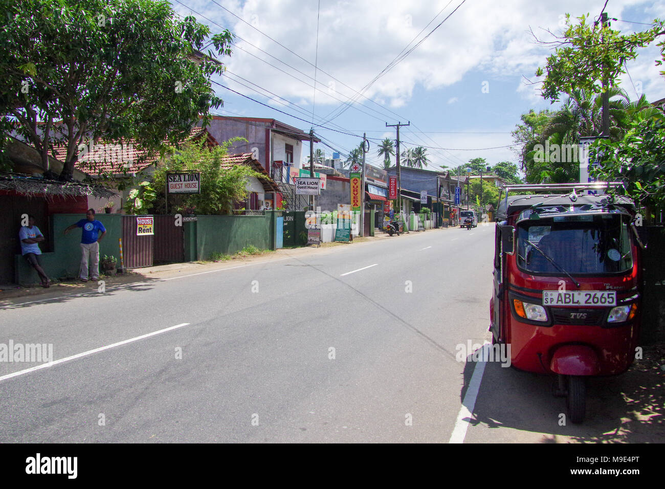 Hikkaduwa village street scene with a tuk-tuk and some locals chatting by the roadside Stock Photo