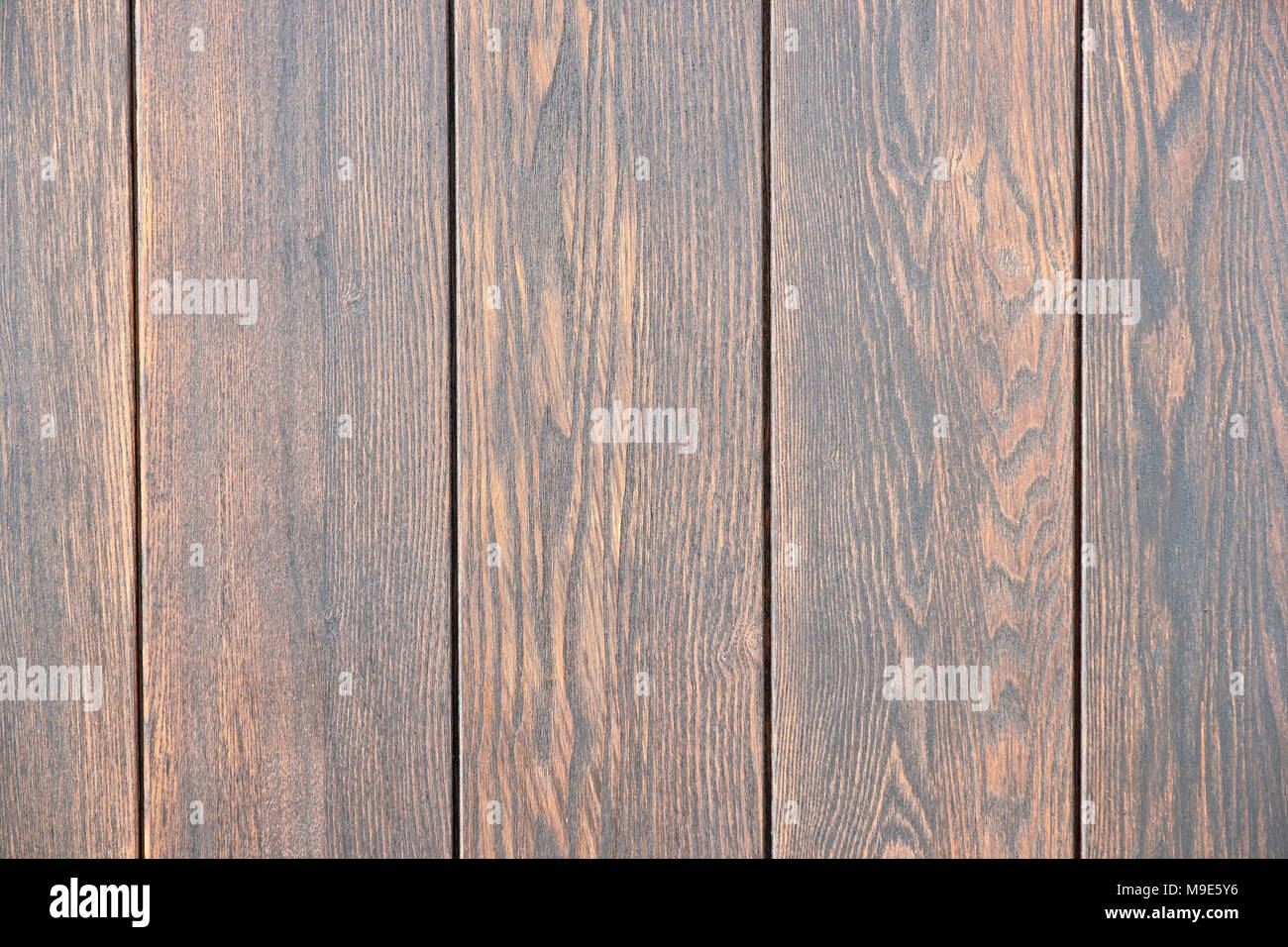 Five vertical wooden planks painted dark brown. Closeup view Stock Photo