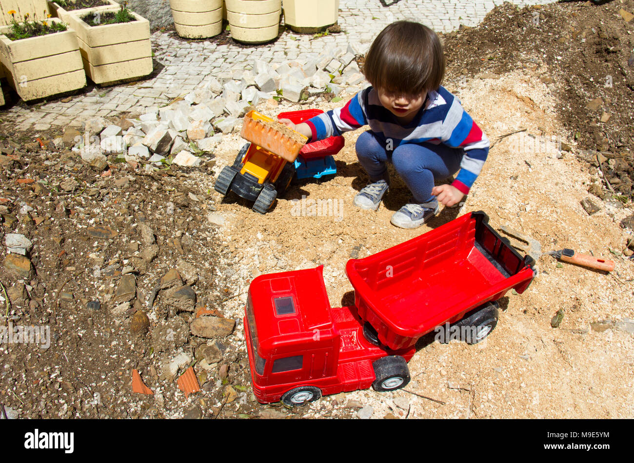 Little Three Year Old Boy Playing In The Sand With A Digger And Dump