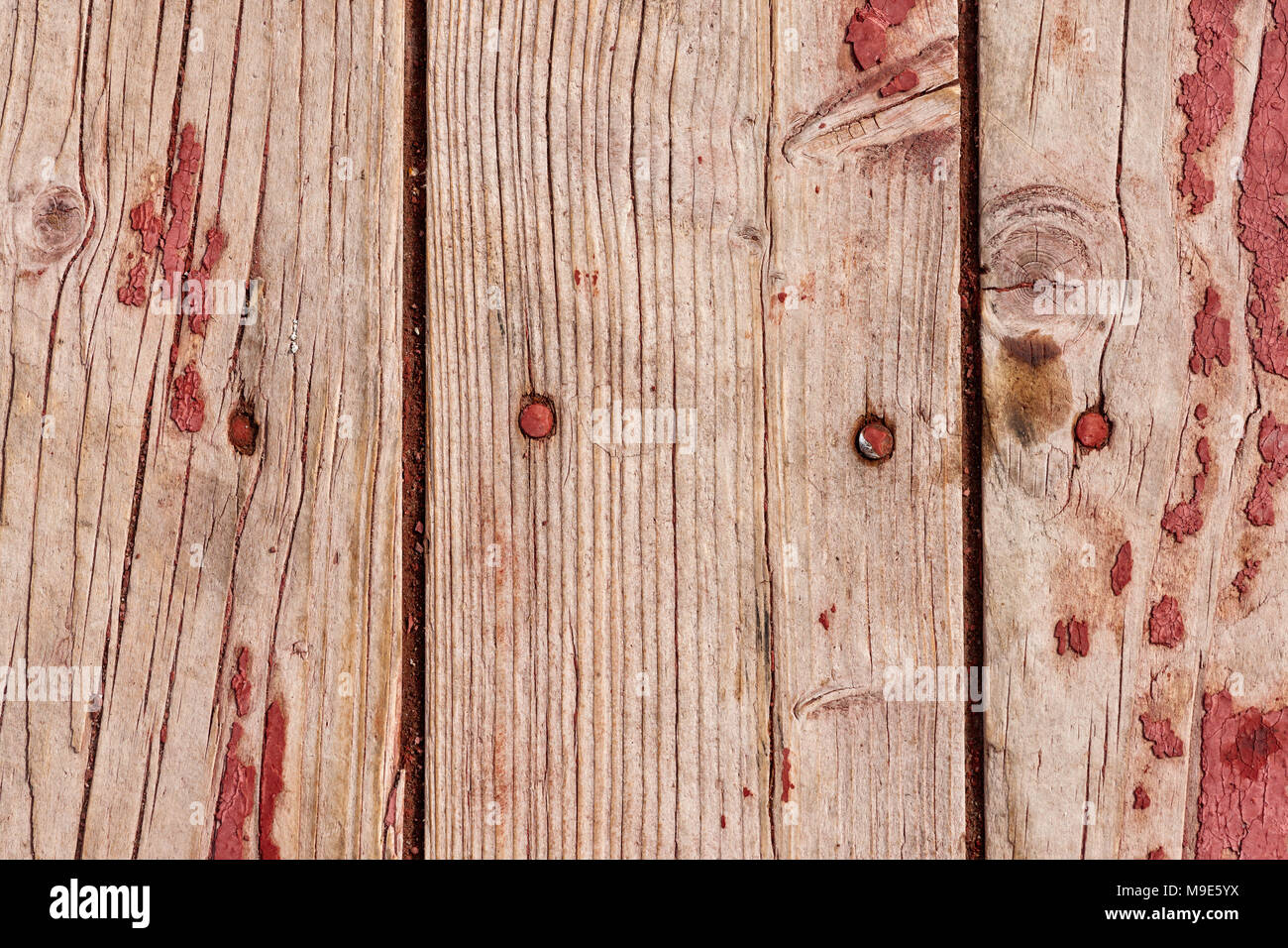 Grunge, weathered vertical wooden planks with a traces of old red or purple paint, nail heads visible Stock Photo