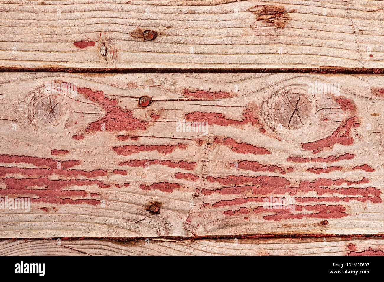 Grunge, weathered horizontal wooden planks with a traces of old red or purple paint, knots or snags visible Stock Photo