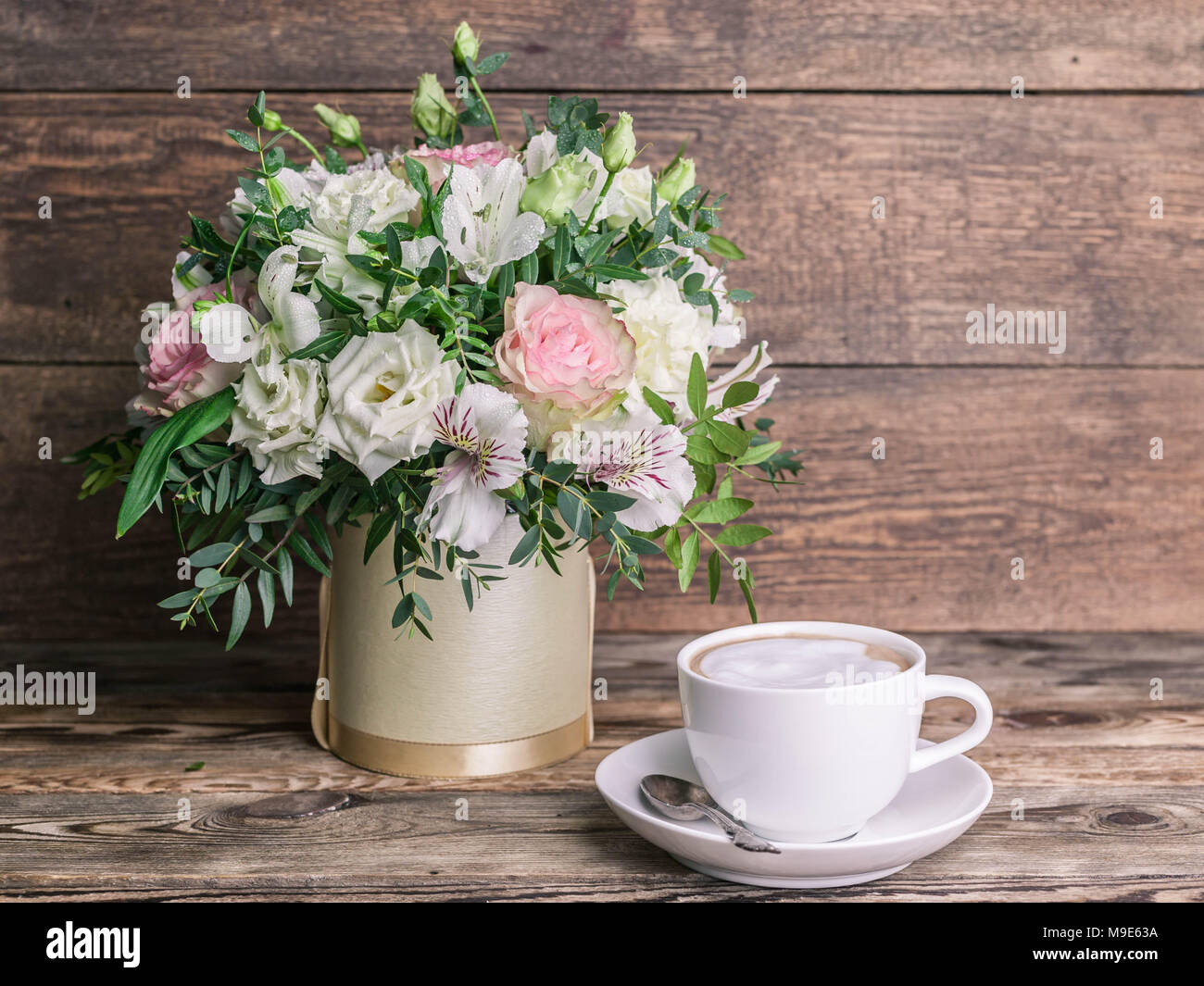 Wedding bouquet in a box and coffee latte in a white cup on a wooden background Stock Photo