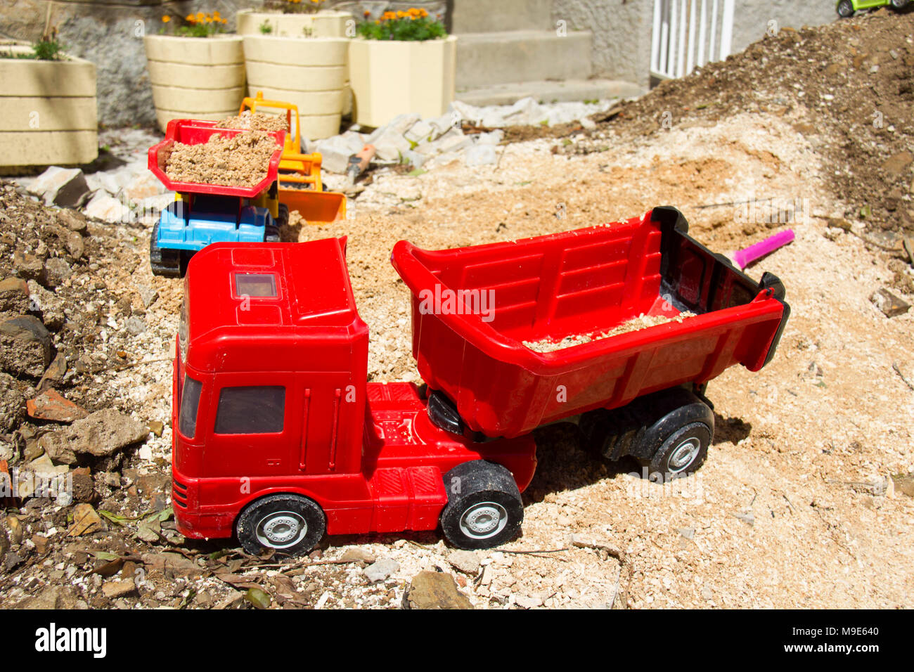 Little boys dumper truck and digger left outside in the sand. Stock Photo