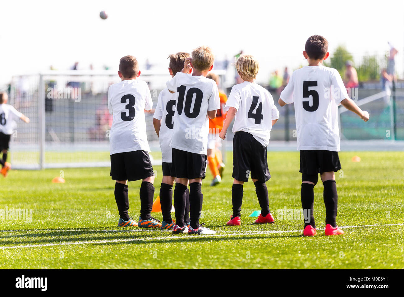 Kids Football Team. Young Boys Watching Soccer Match. Football Tournament Competition in the Background. Children Football Team Players on The Soccer  Stock Photo