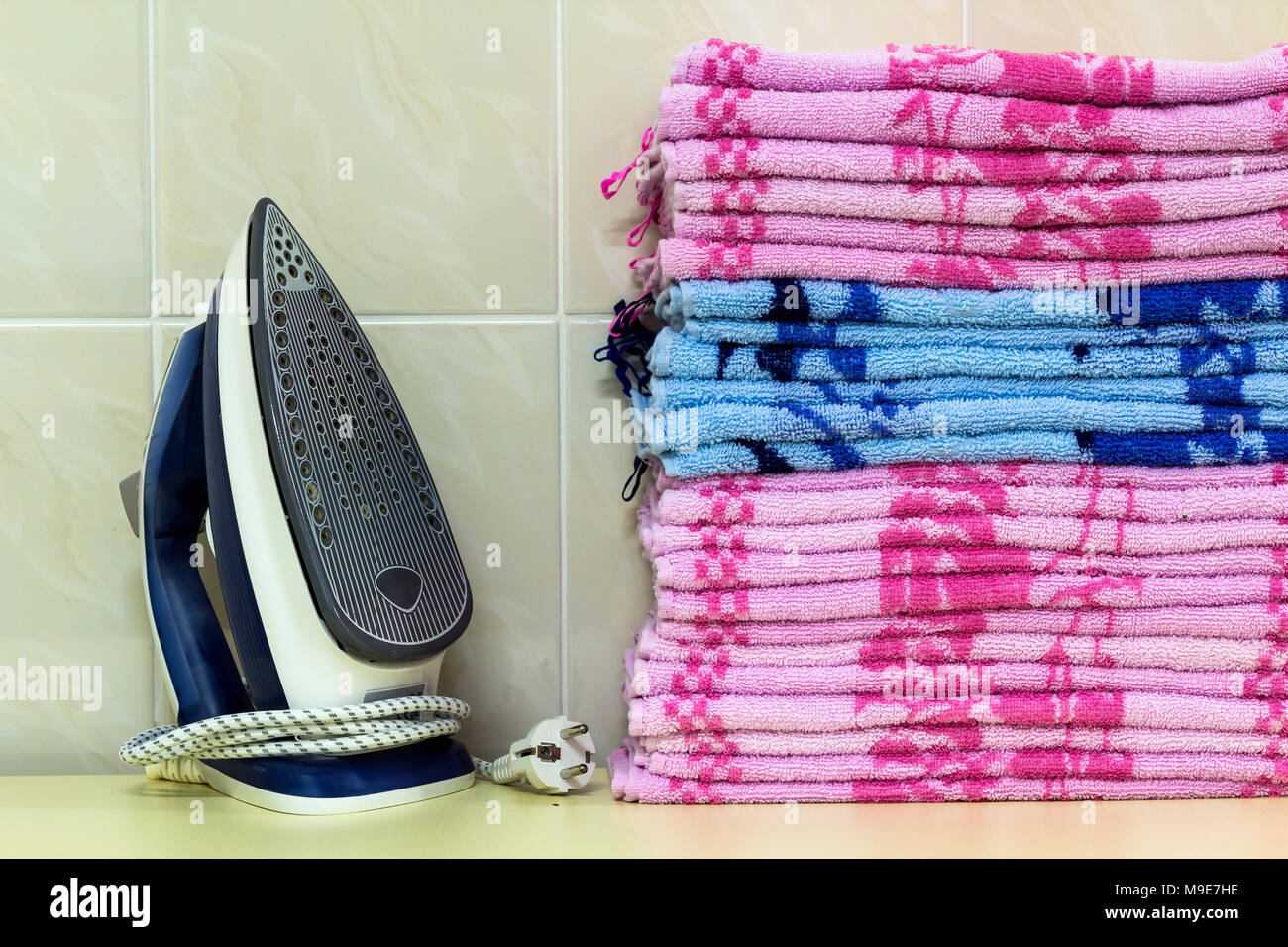 Ironing linen with steam generator. A stack of ironed towels lying next