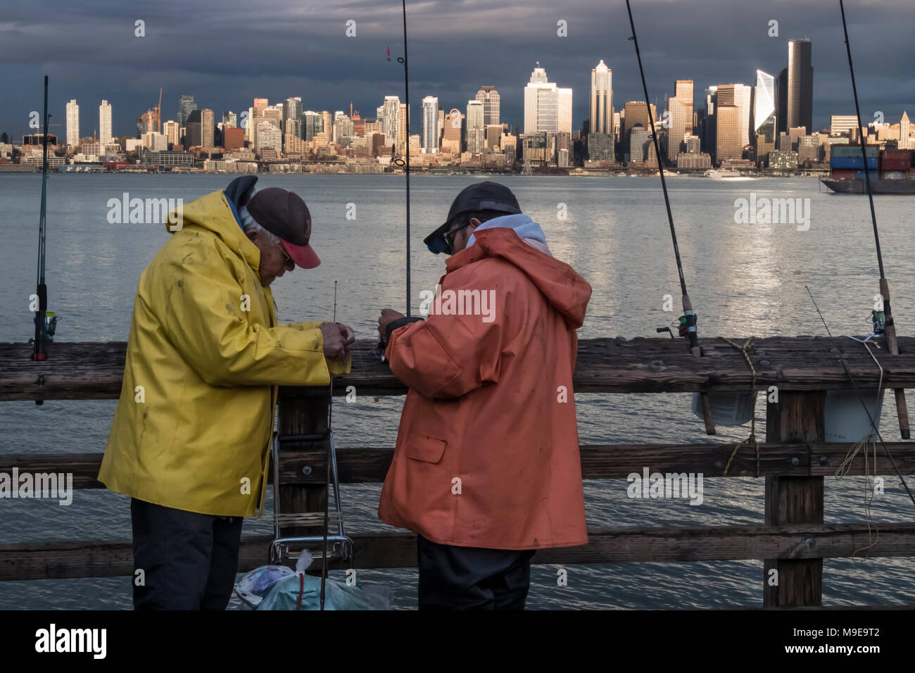 Two fishermen on pier across Elliott Bay from downtown Seattle, Washington, USA Stock Photo